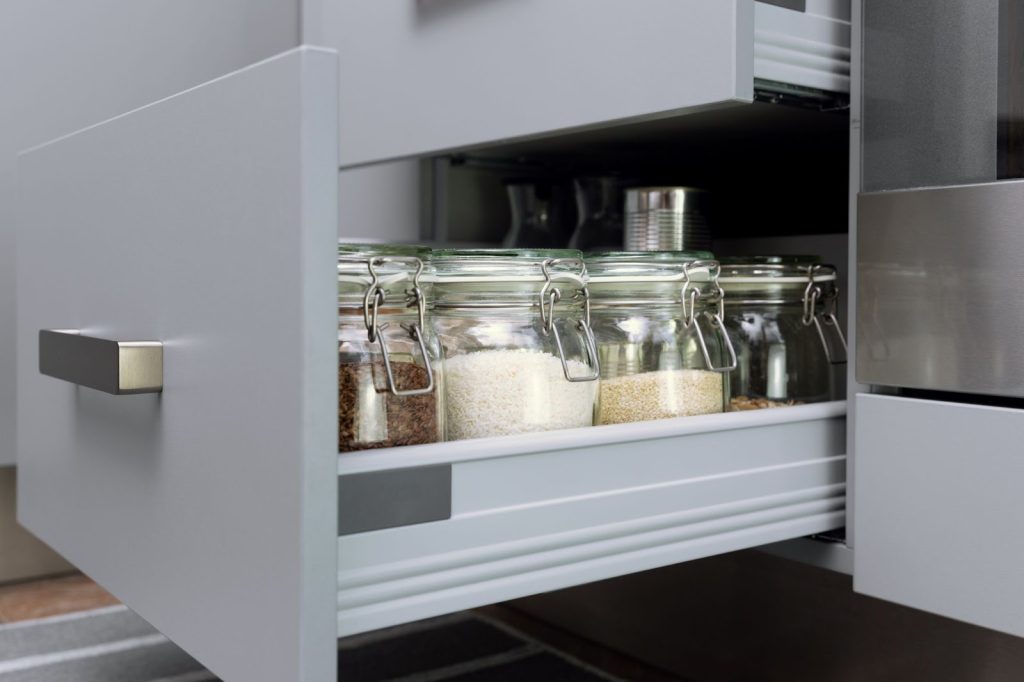 Kitchen drawer with jars of spices and salt in custom kitchen cabinets.